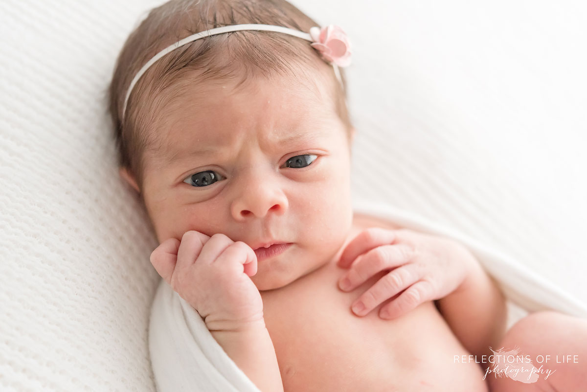 Newborn baby girl with headband questionning life