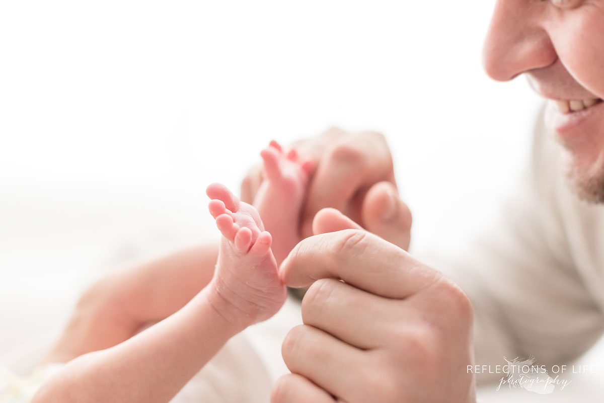 Cute daddy playing with newborn baby toes