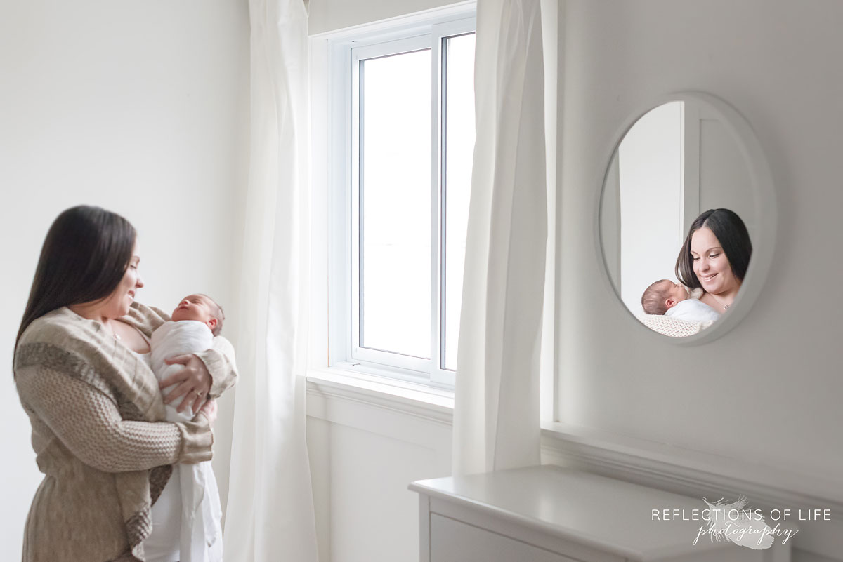mom and newborn daughter in natural light studio with mirror reflection.jpg