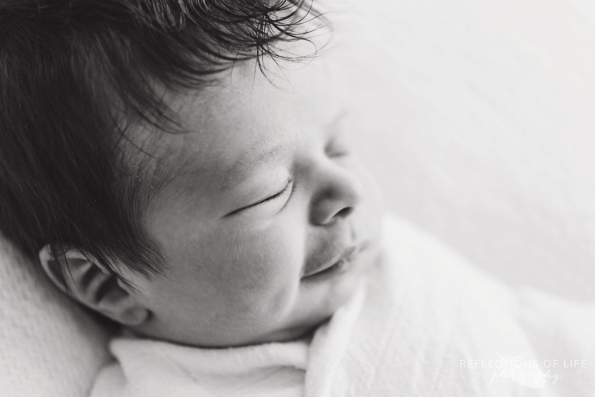 close up of newborn baby girl in black and white