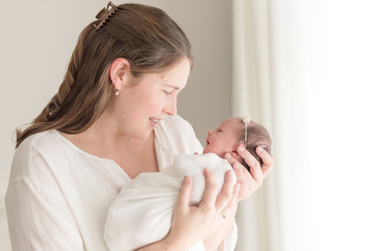 candid photo of mom holding newborn baby girl with love