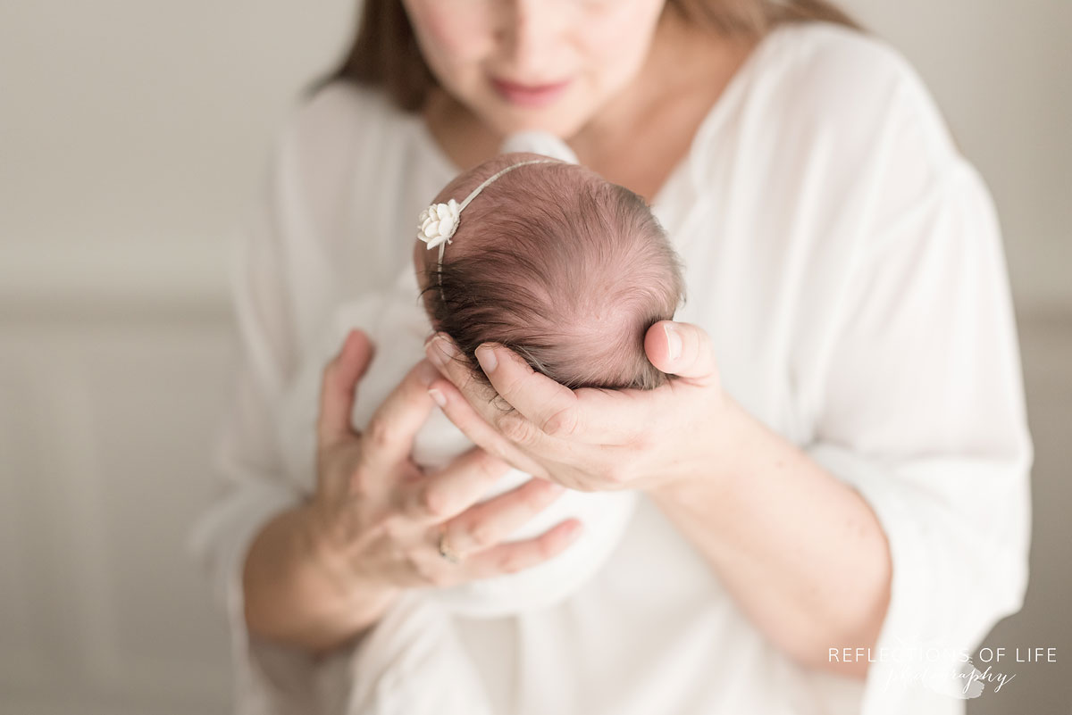 mom holding newborn baby girl with beautiful hair