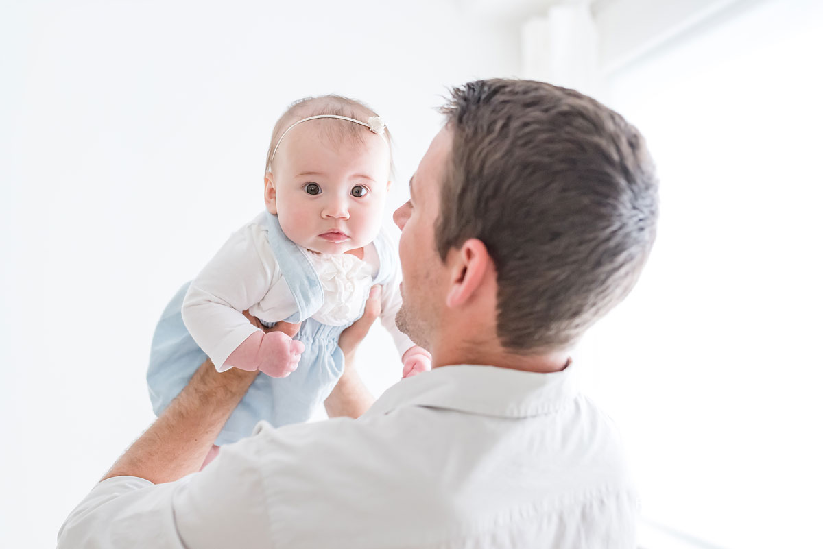 Father holding baby up in white studio