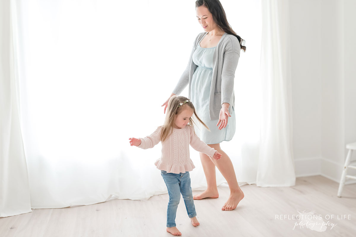 Mother and daughter dancing in white studio