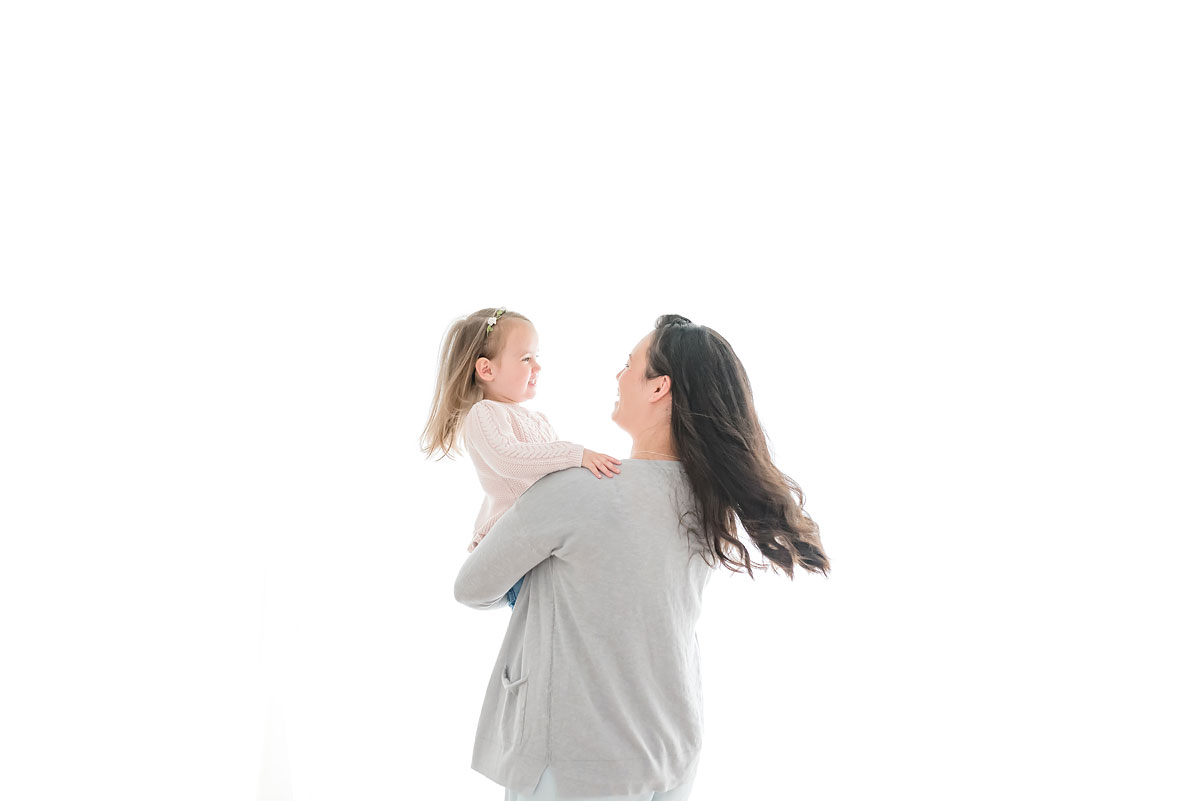Mother and daughter twirling in white studio