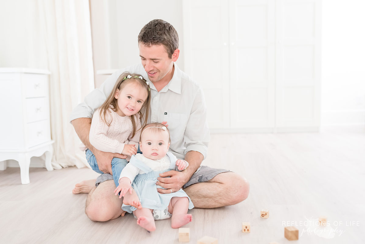 Father and children sitting on floor in white studio