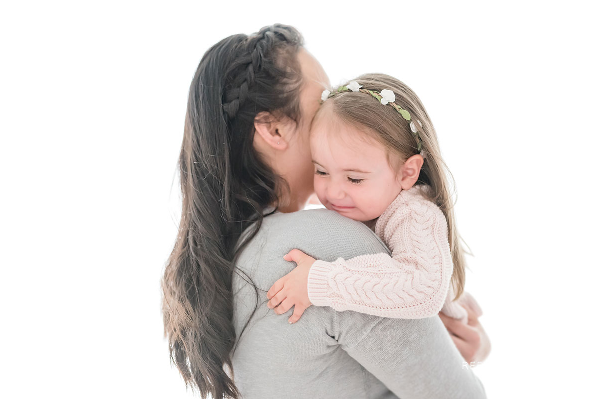 Mother and daughter hugging in white studio