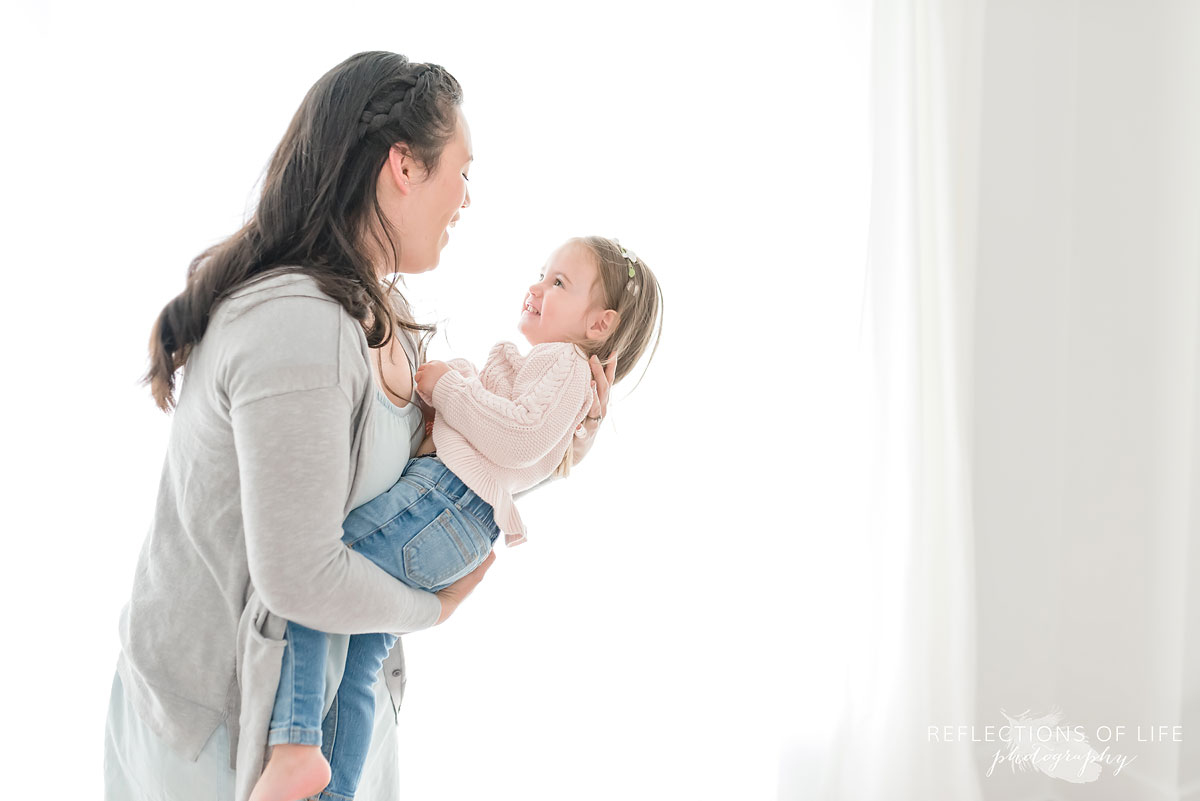 Mother and daughter playing around in white studio