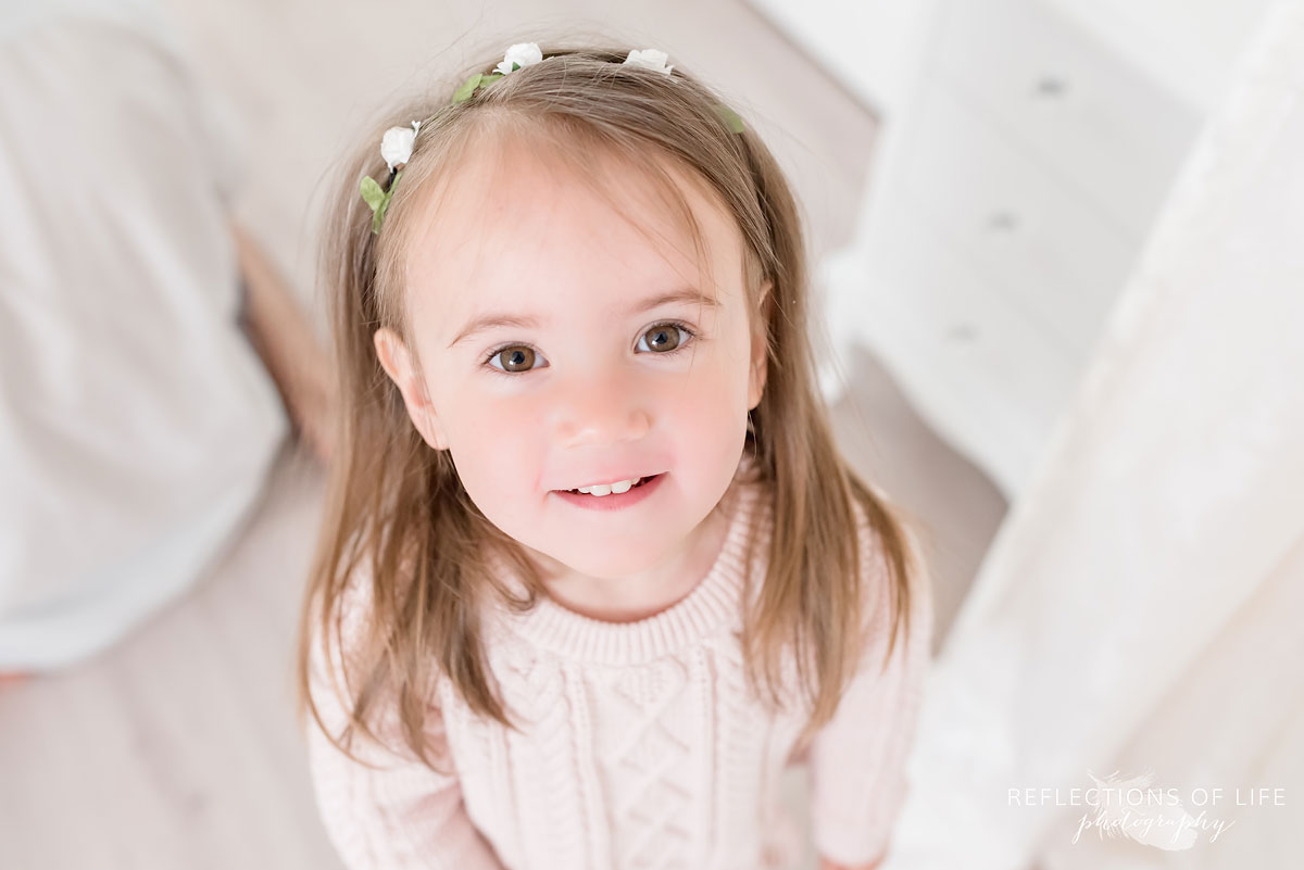 Young girl smiling at camera in white studio
