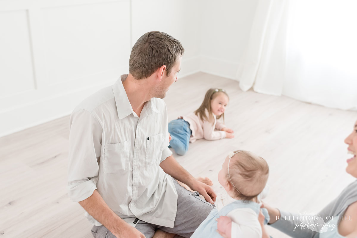 Father and mother watching children play in white studio