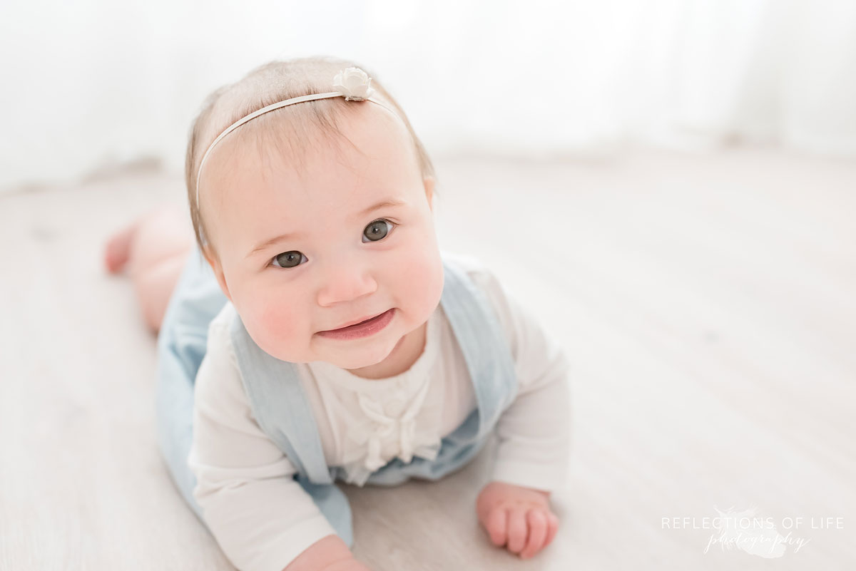 Baby smiling with flower headband on in white studio