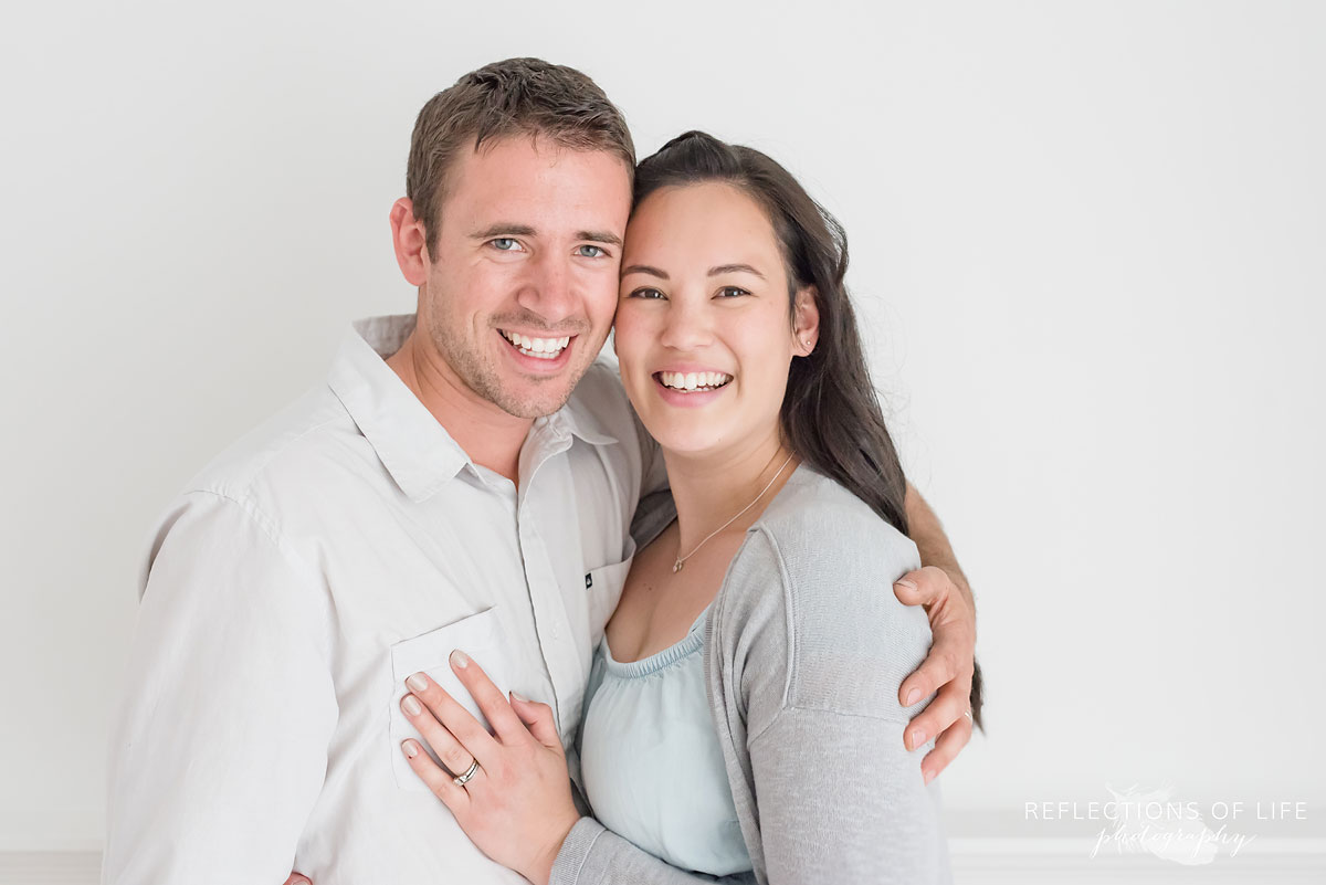 Husband and wife smiling in white studio