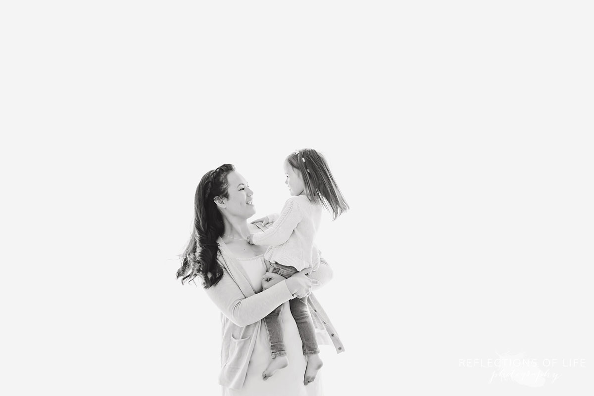 Mother and daughter looking into eachother's eyes in a white studio