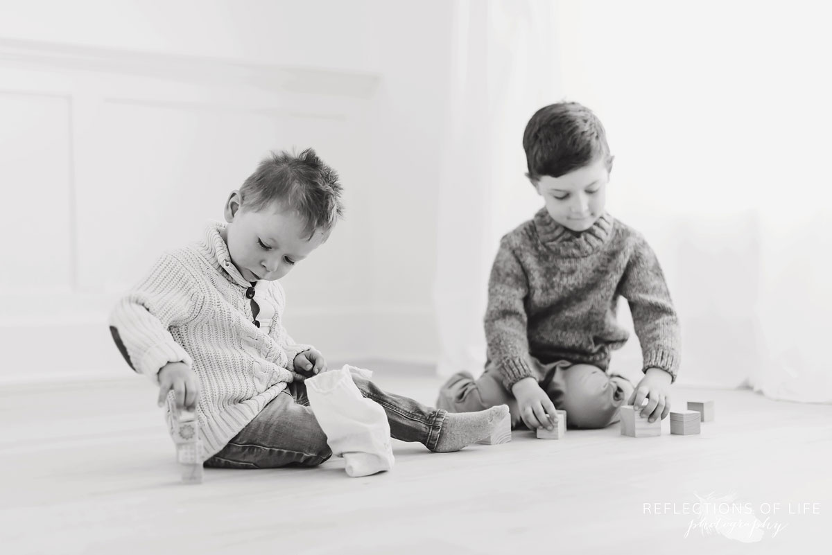 Brothers building wooden block towers in black and white
