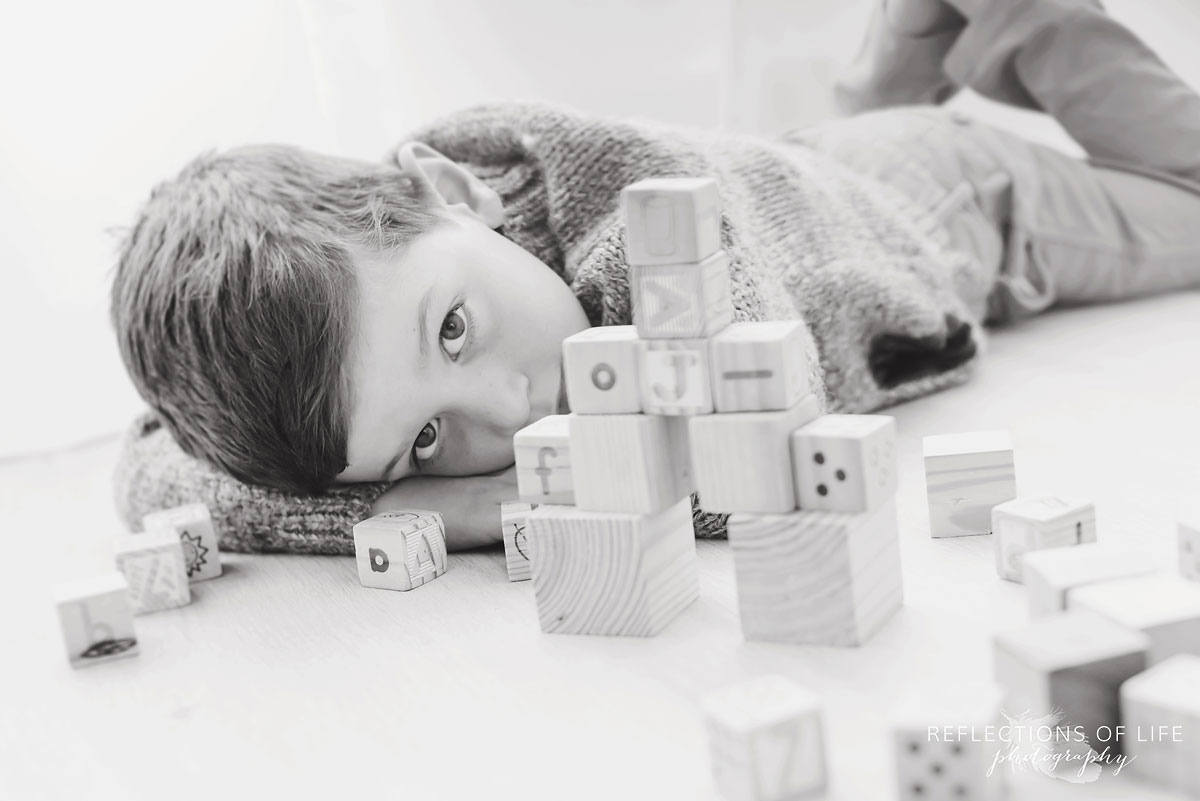 little boy relaxing while playing with wooden blocks