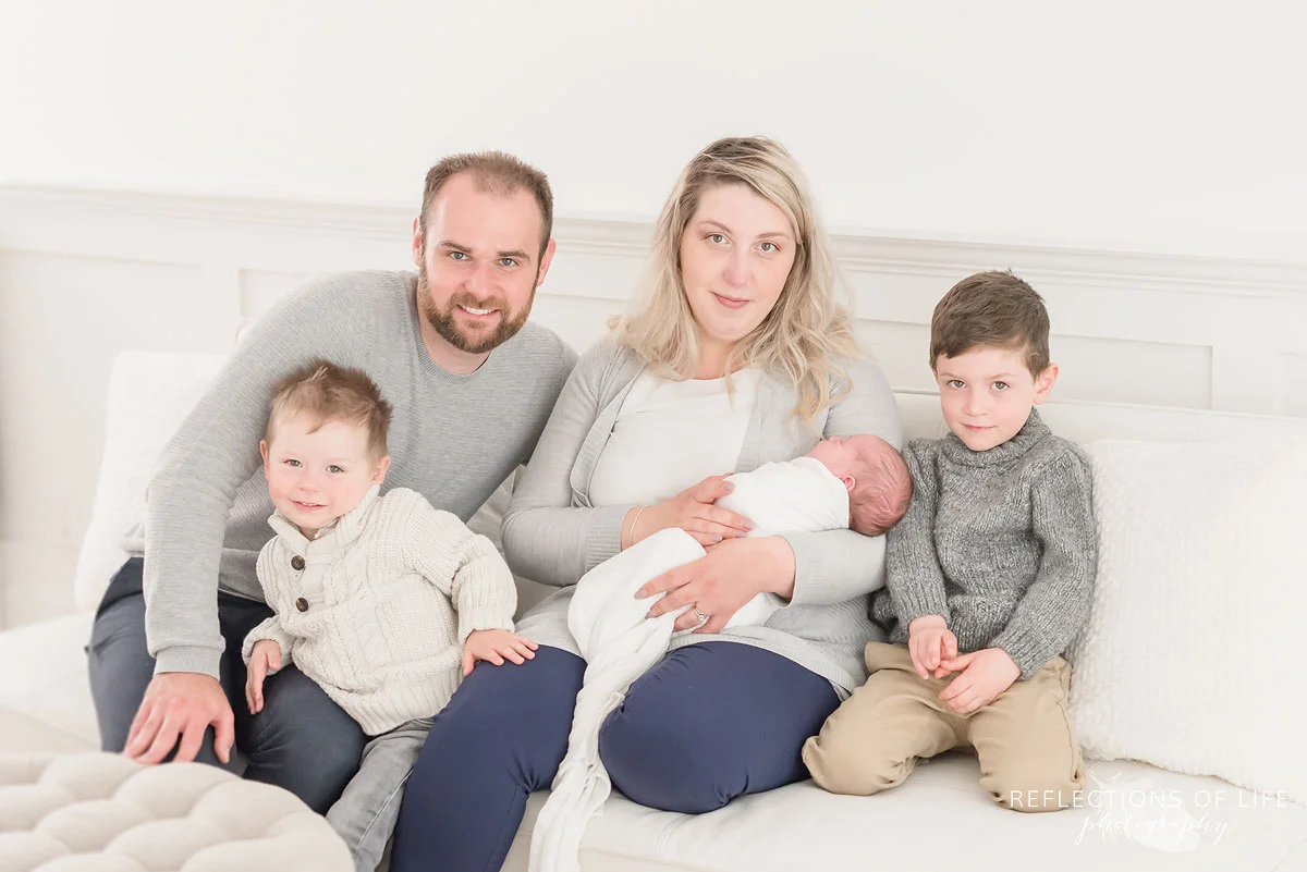 Sweet family photo of mom dad and siblnigs with their newborn baby