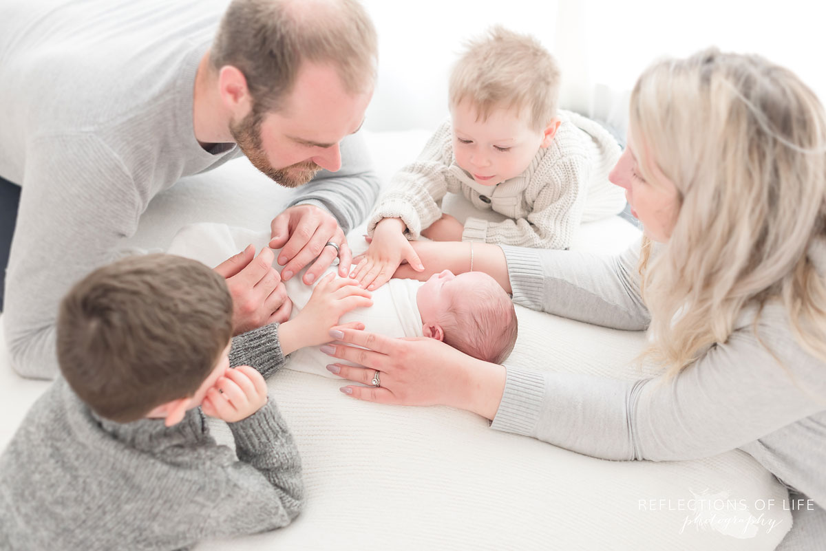 Family photo of everyone looking down at their newborn baby son