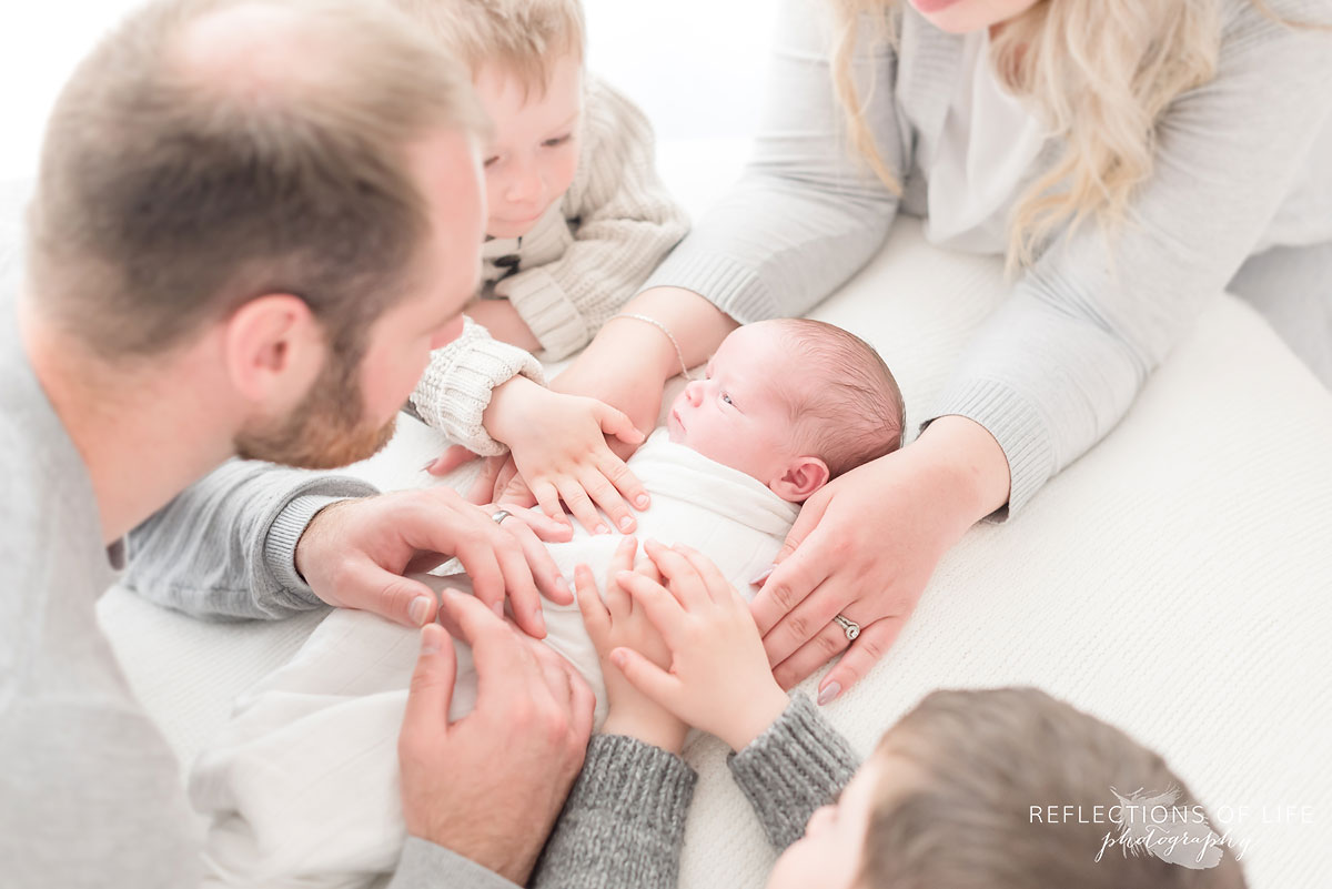 Family photo of baby boy with everyones hands on him
