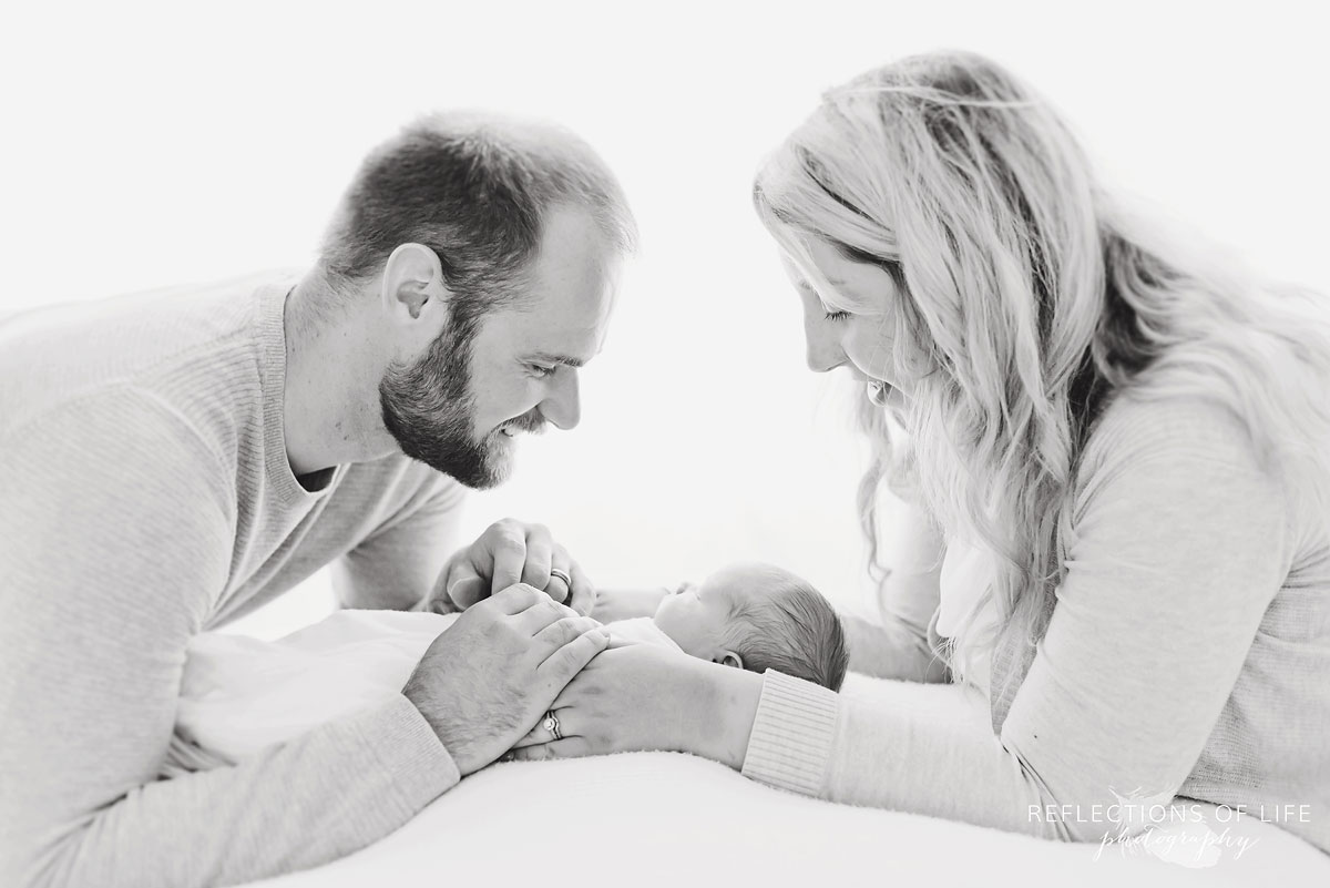Adorable photo of parents looking down at their new baby boy in black and white