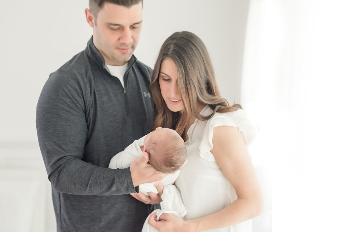 Mother and father looking at baby in white studio
