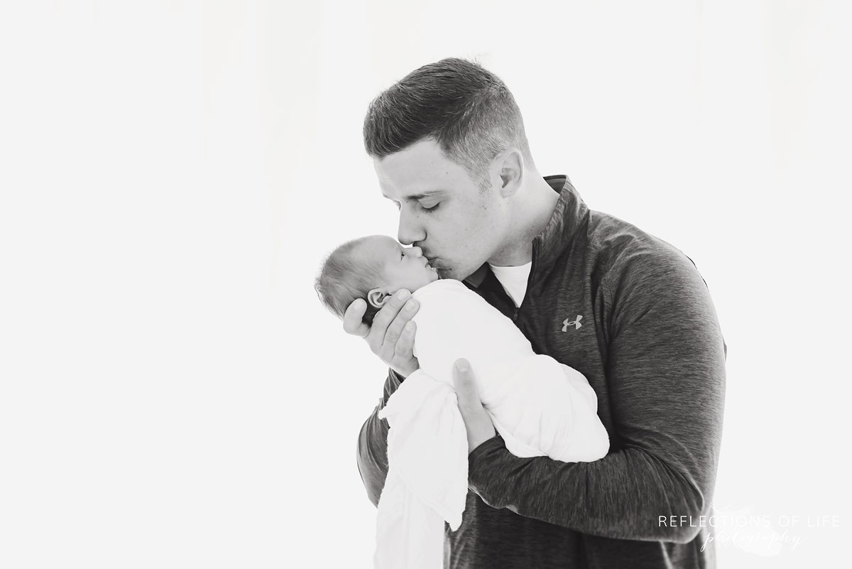 Father kissing his baby girl black and white