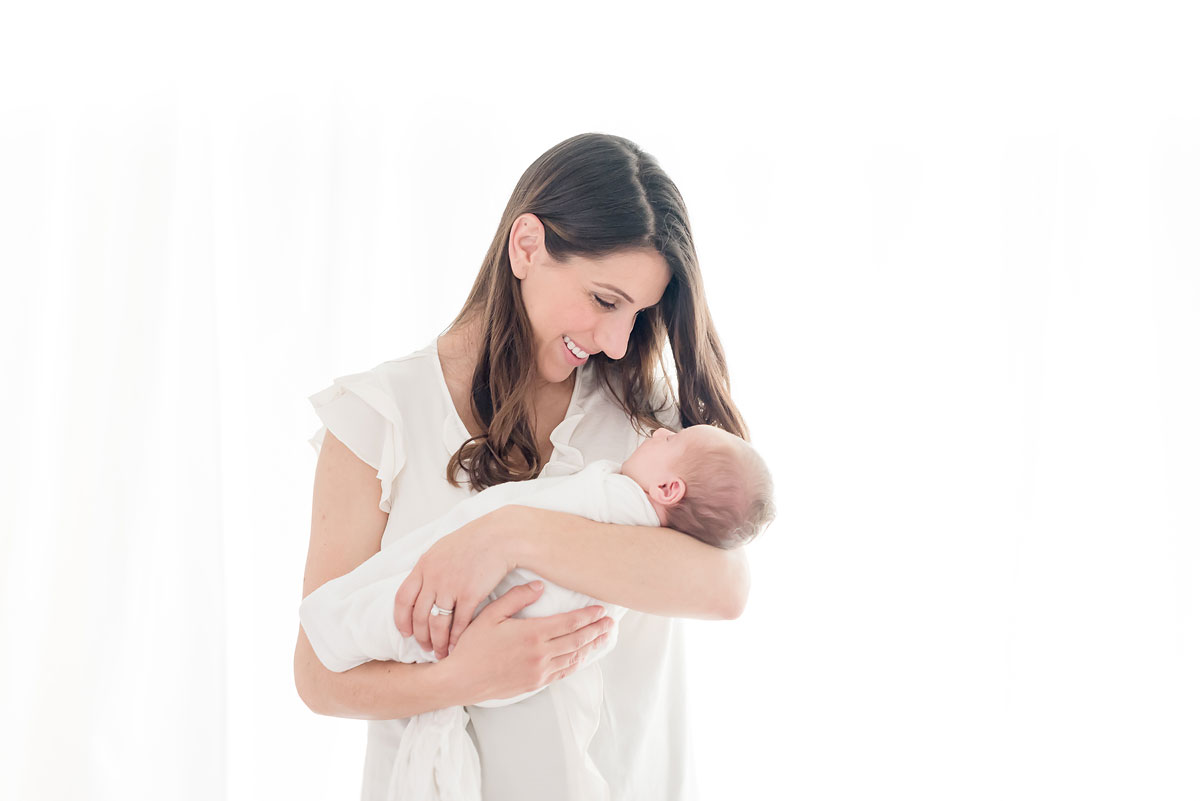 Mama smiling at her baby girl in white studio