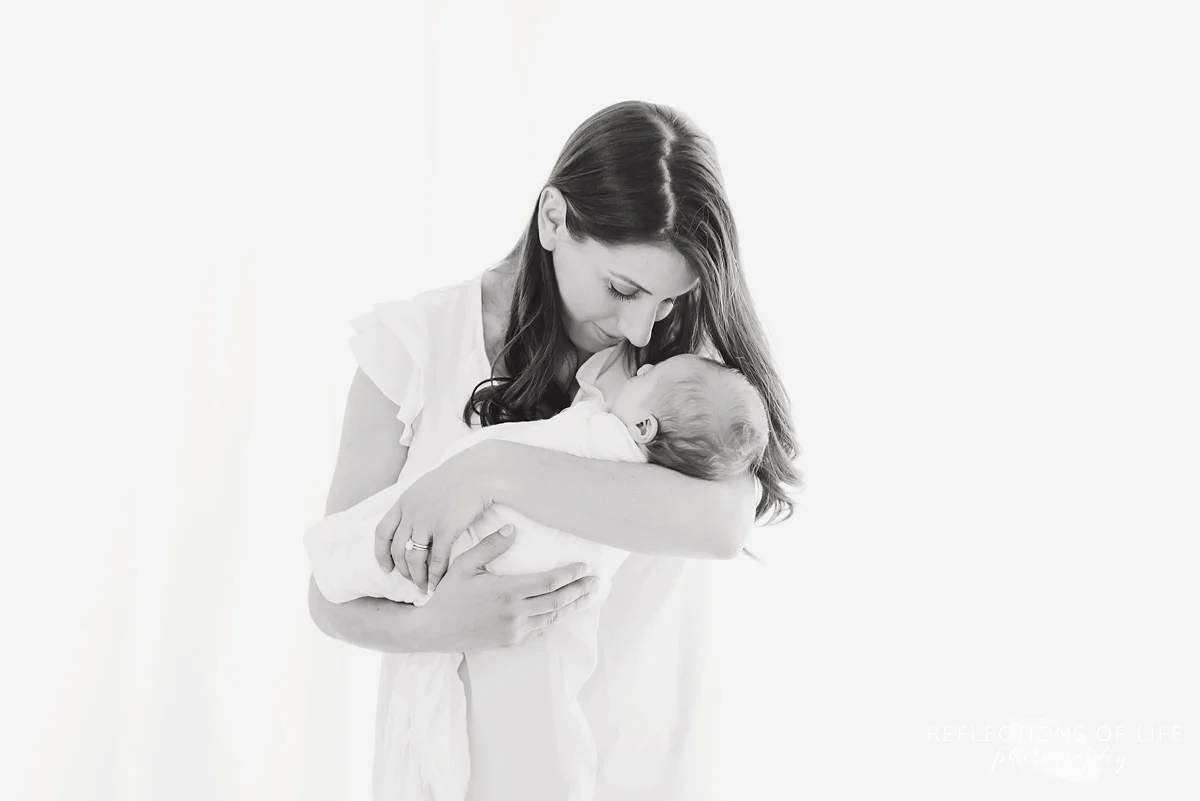 Mama smiling at her baby girl in white studio