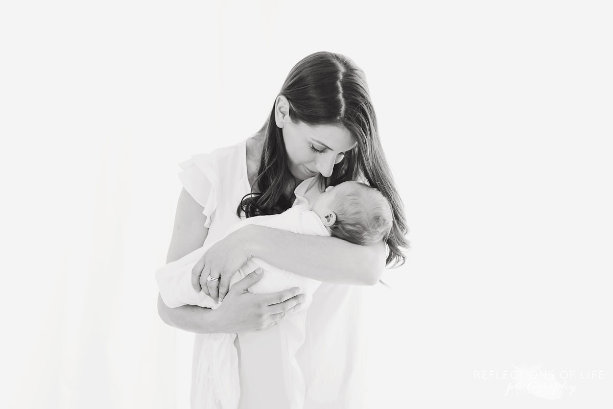 Mama smiling at her baby girl in white studio