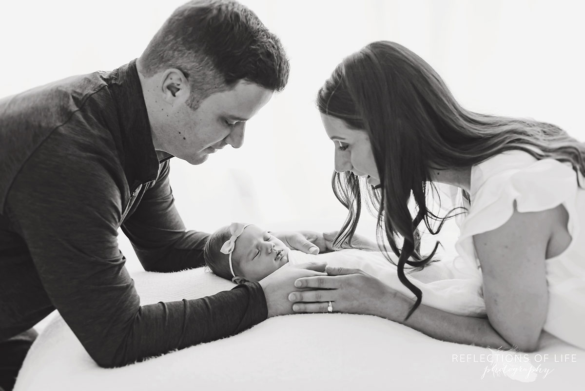 Mother and father holding baby on opposite sides black and white