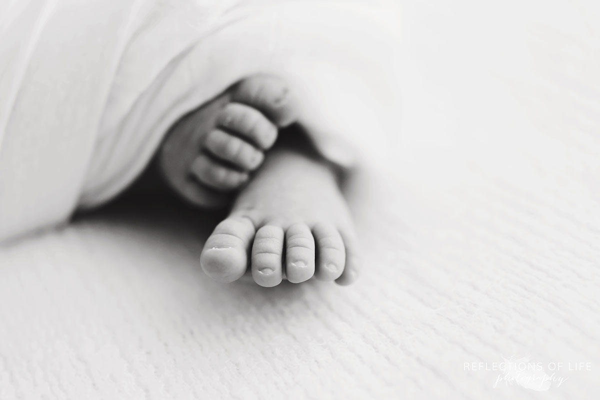 Baby toes wrapped in a blanket in black and white