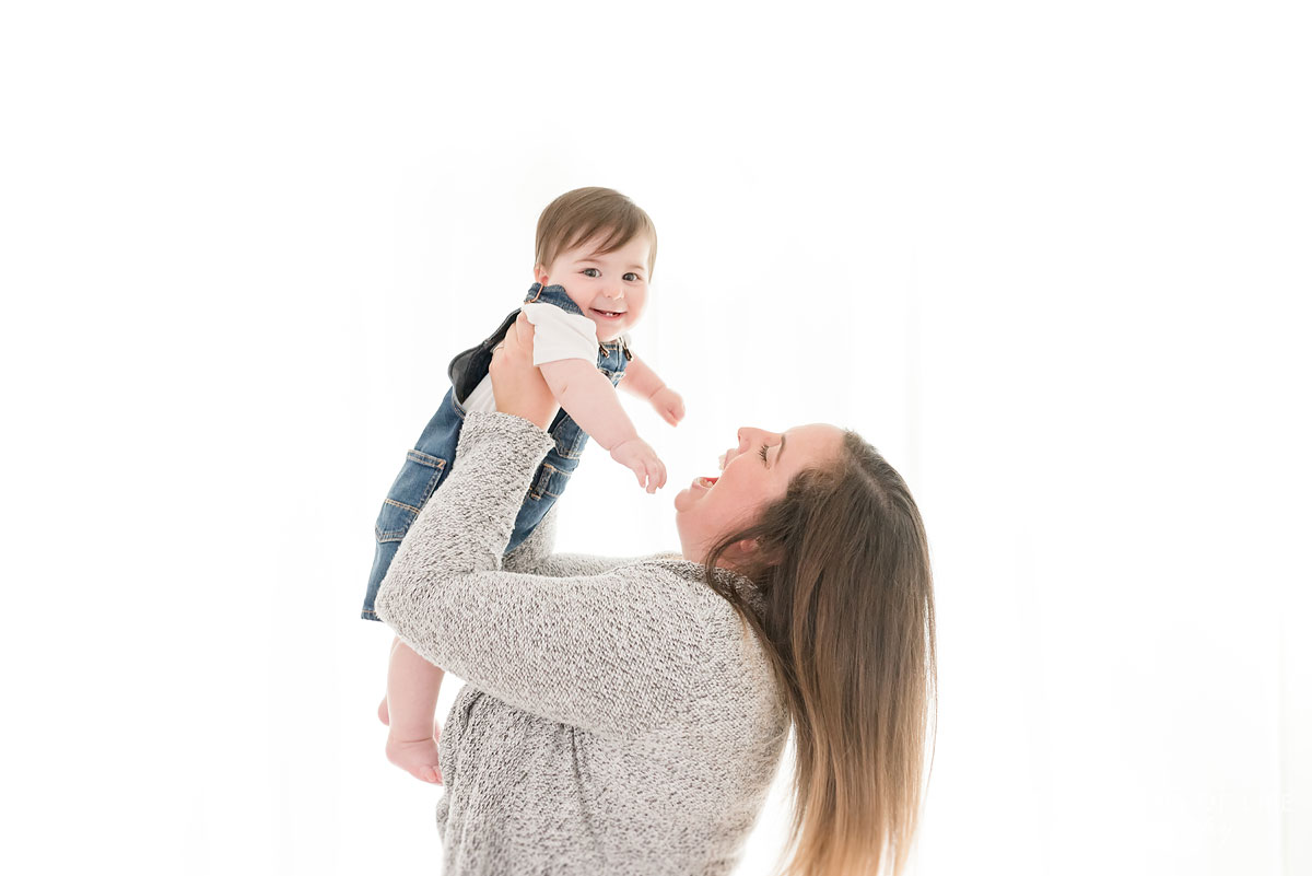 Mother swinging baby around in white studio