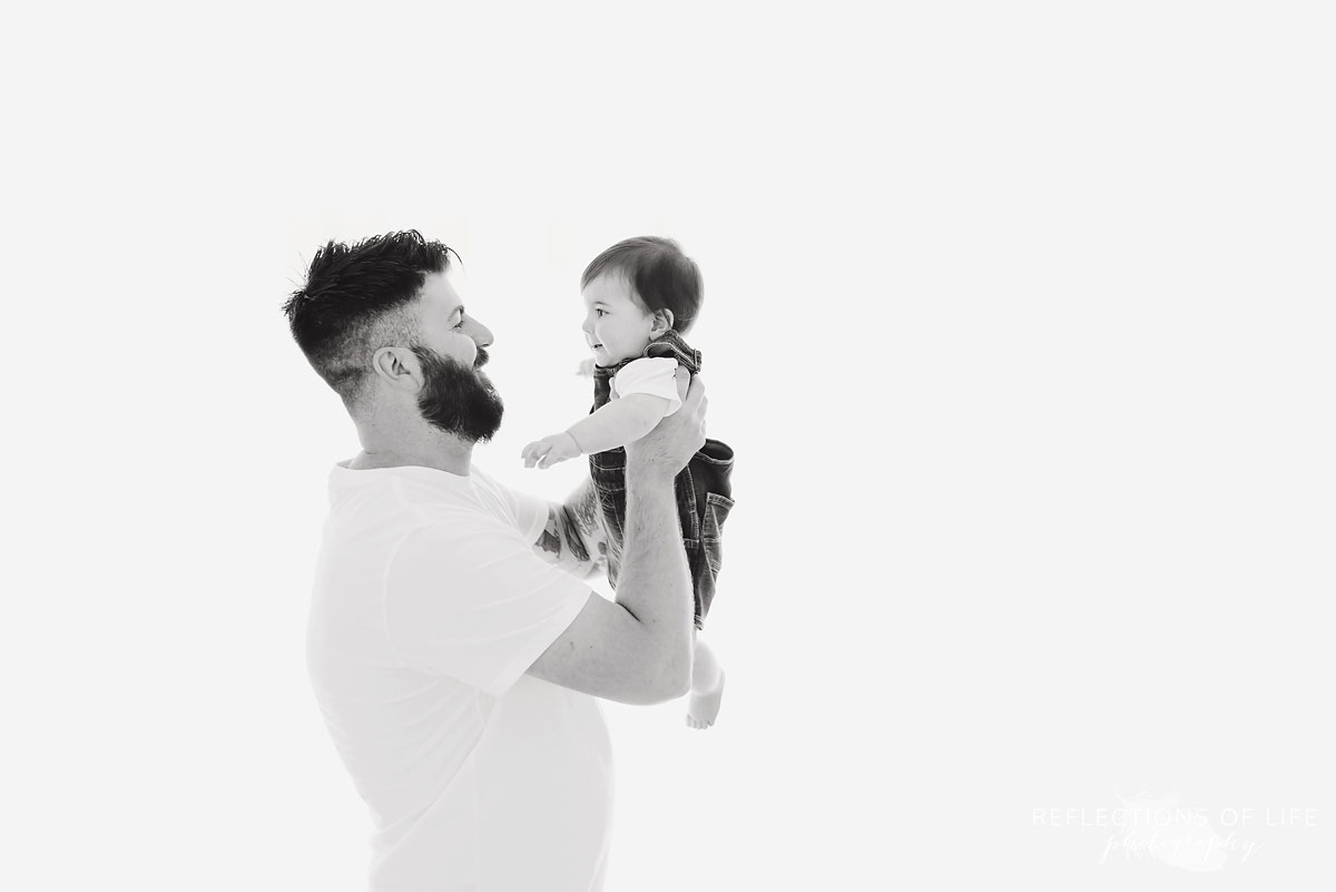 Father smiling baby white holding him up in black and white