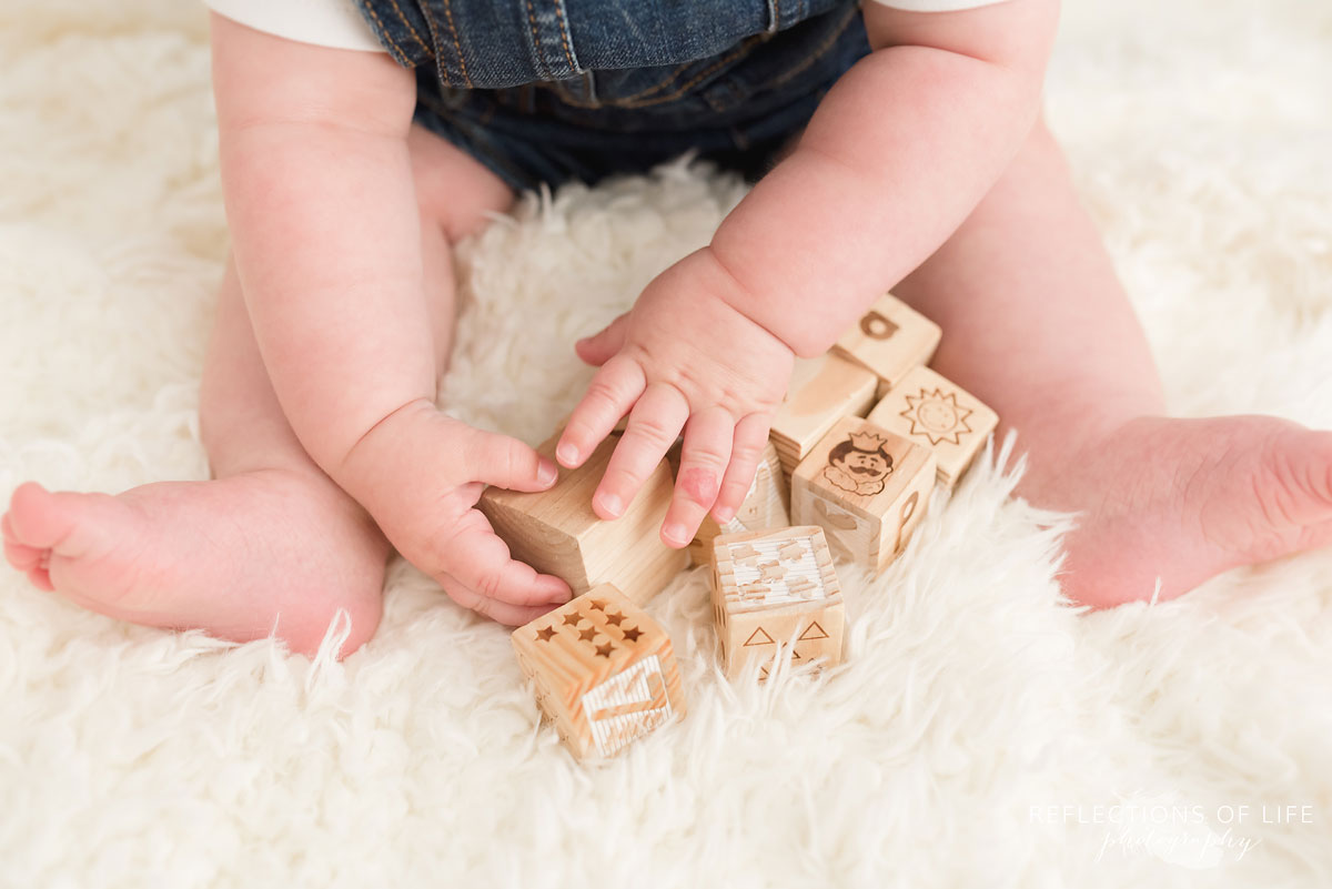 Baby playing with wooden blocks on white blanket