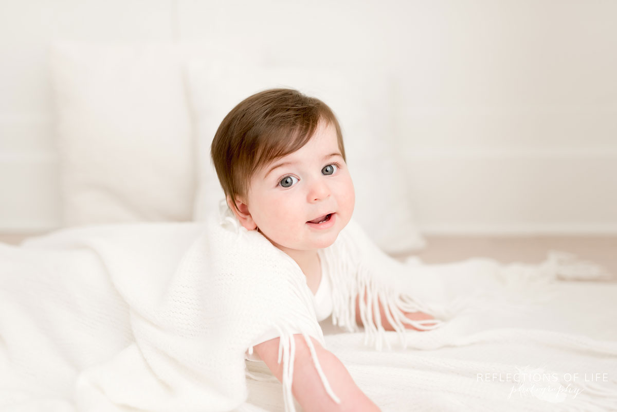 Baby looking at camera and smiling in white blankets
