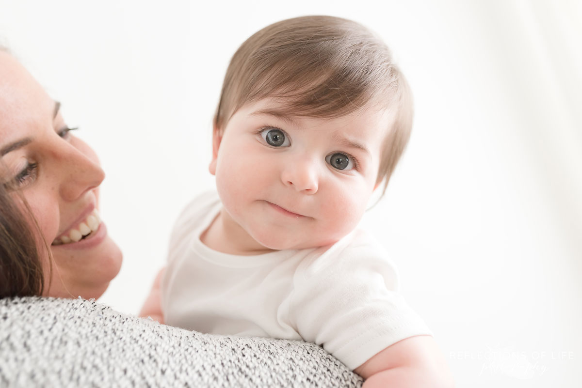 Mother laughing at baby in white studio
