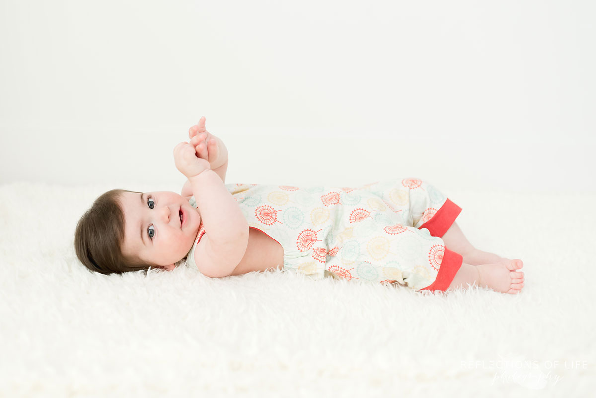 Baby looking at camera on white blanket in white studio