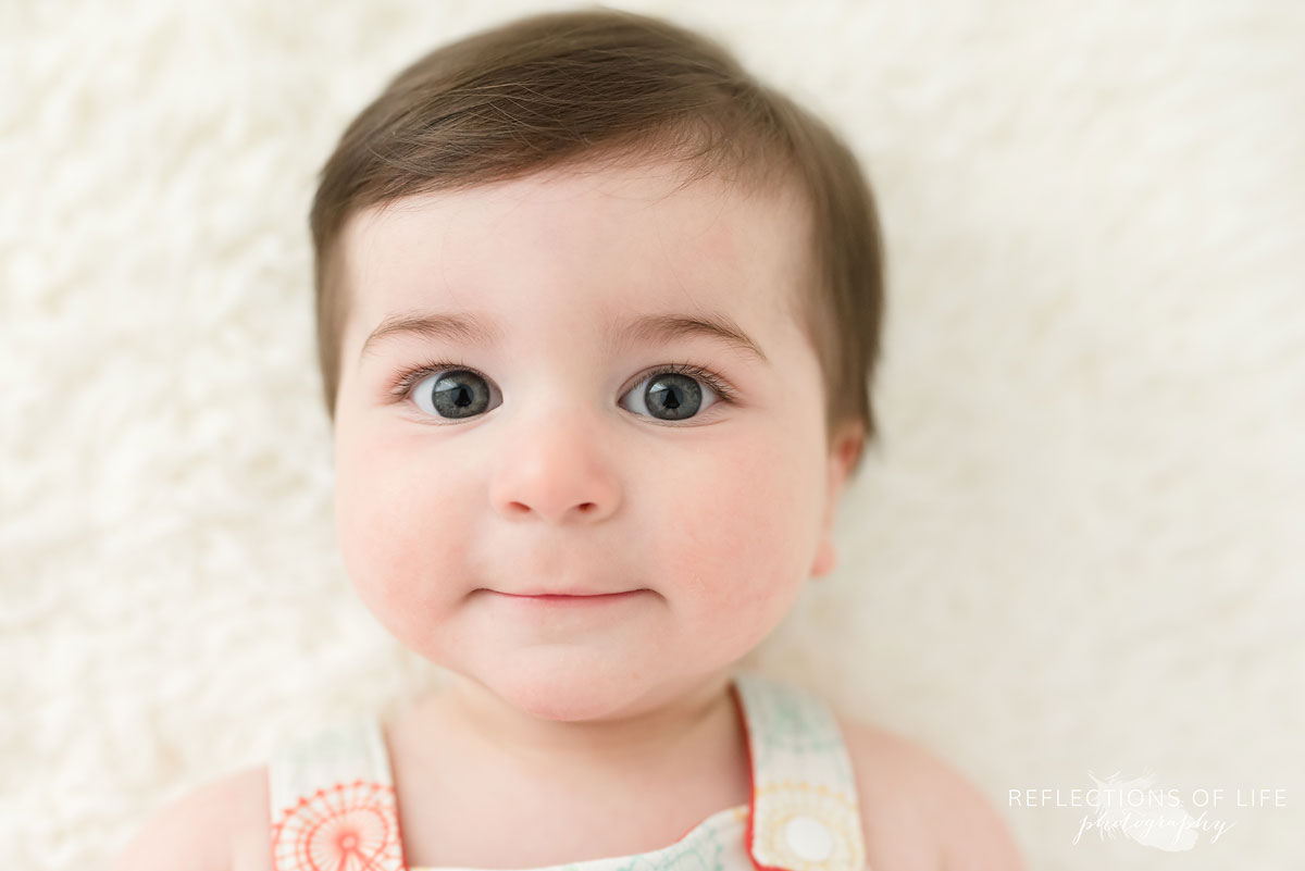 Baby smiling at camera on white blanket