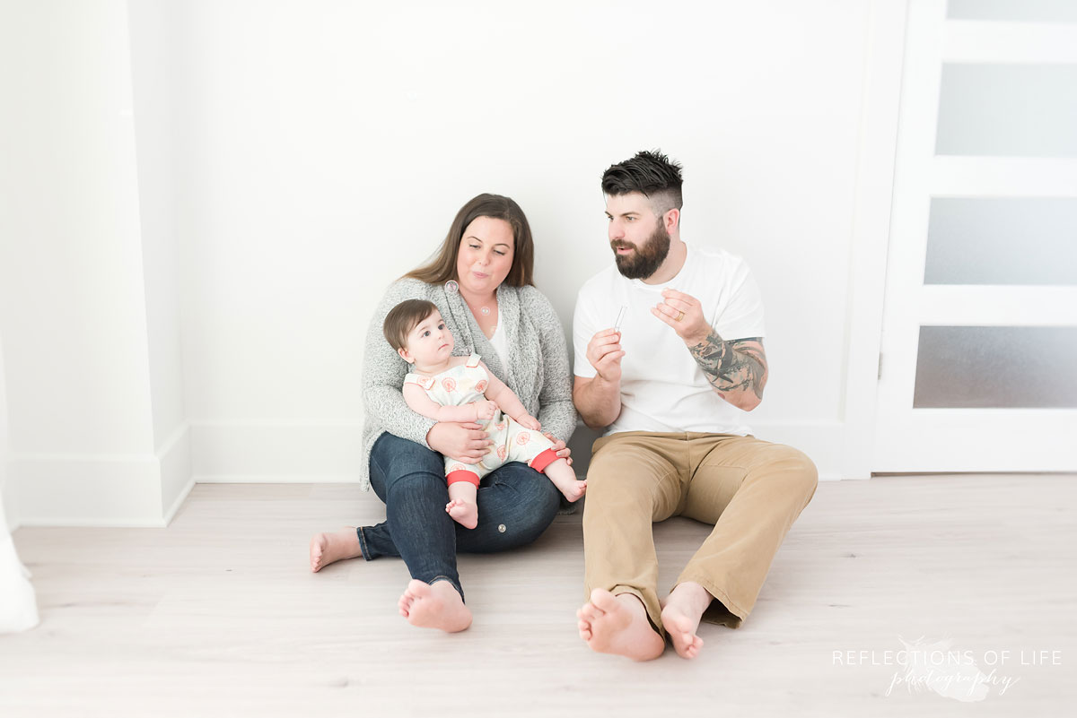 Family of three sitting on floor in white studio