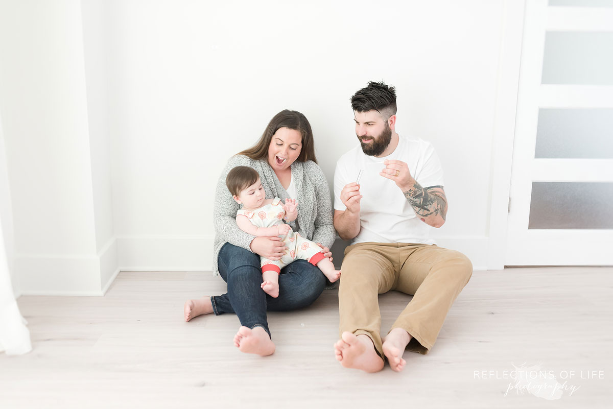 Mom dad and baby on floor in white studio Grimsby ontario