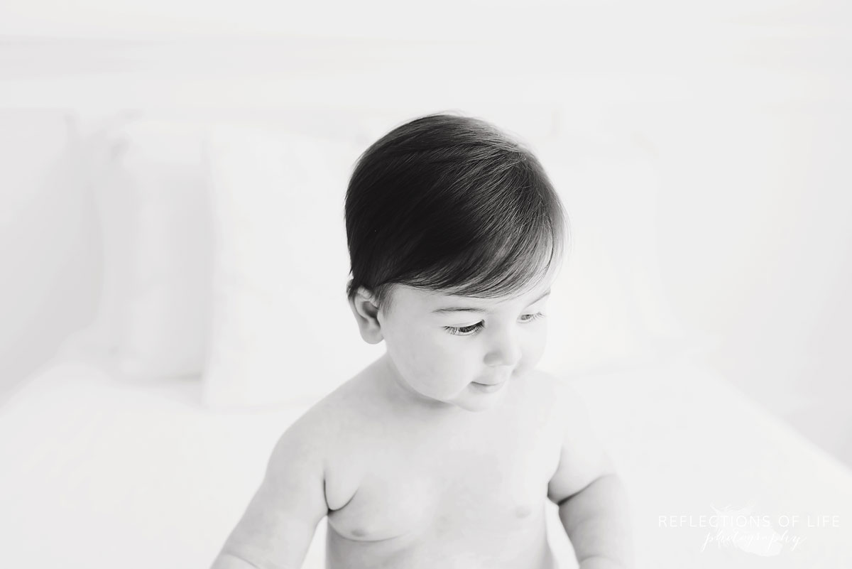 Black and white of baby looking down on white couch