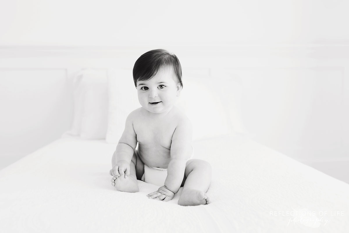 Black and white of baby in diaper on white couch