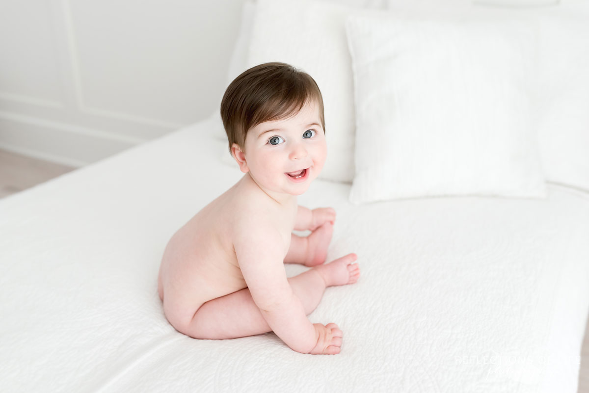 Baby with no clothes on white couch in Niagara