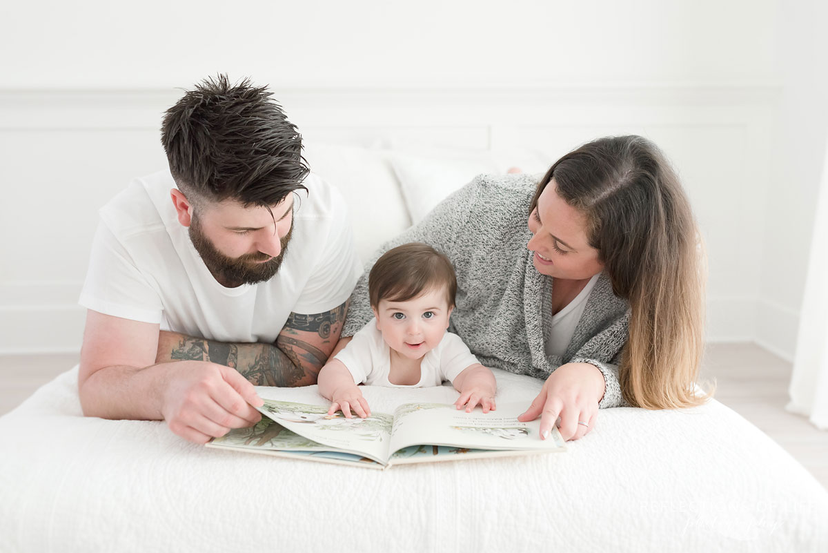 Mom and dad reading book to smiling baby