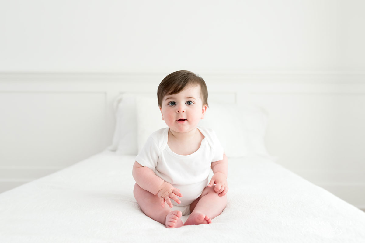 Baby with open mouth on white couch in Niagara