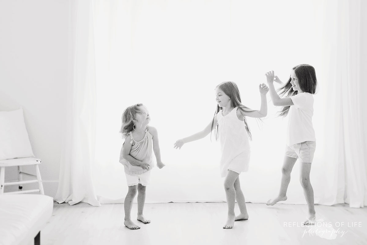 three sisters dancing in white studio