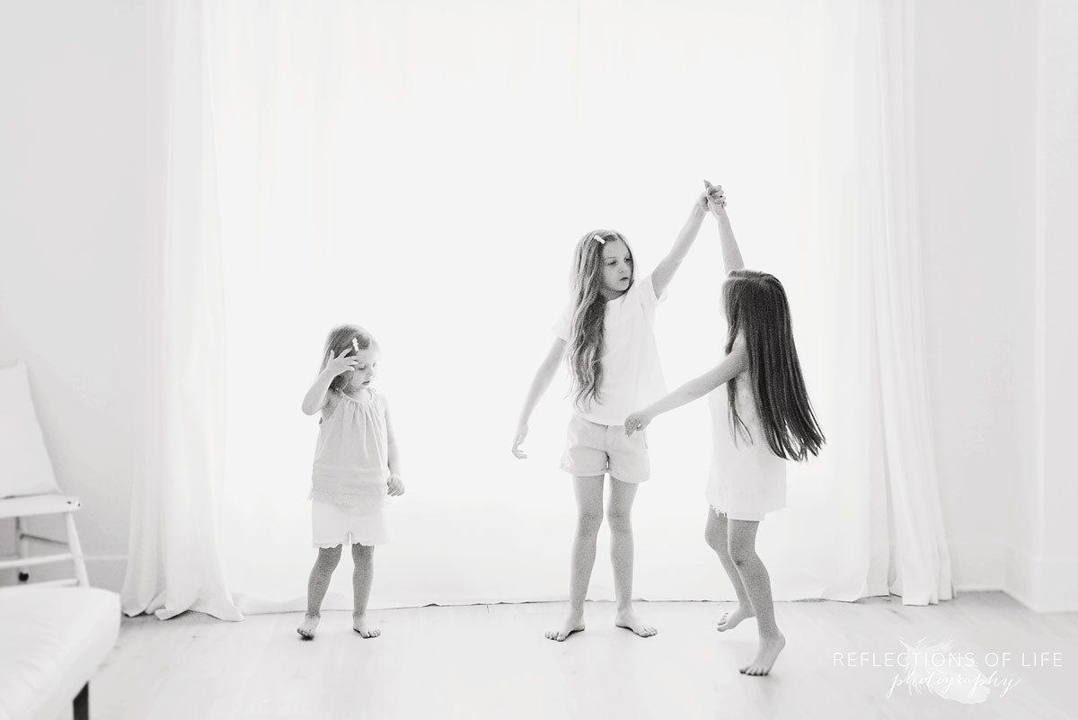 portrait of three sisters spinning each other in front of white background