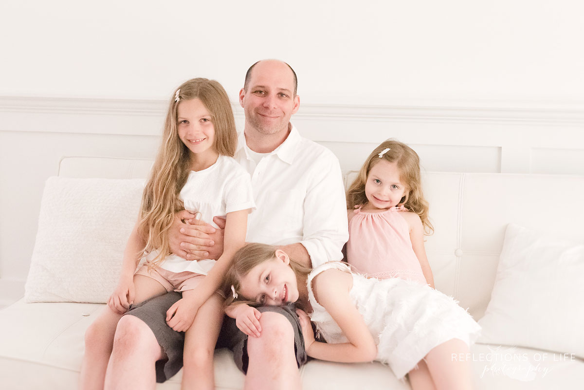 dad and daughters sitting on couch in studio