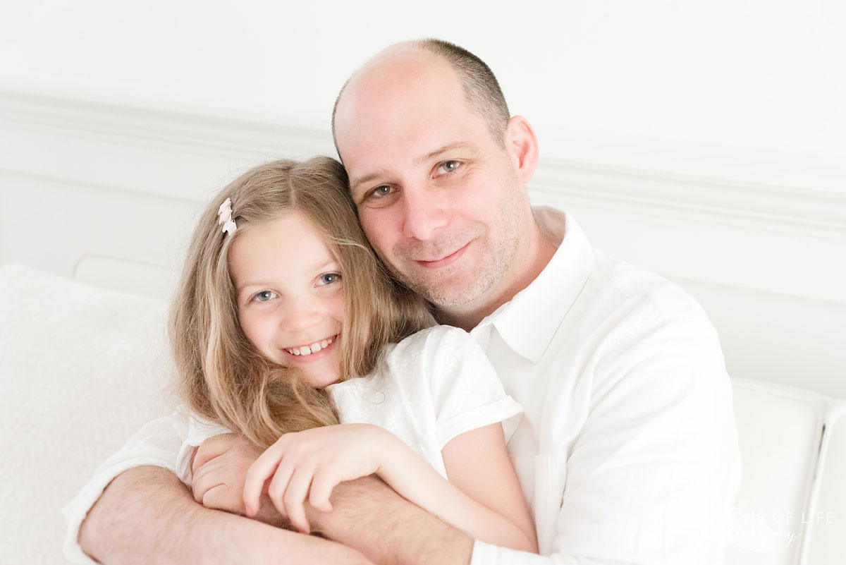 dad and daughter sitting on white couch