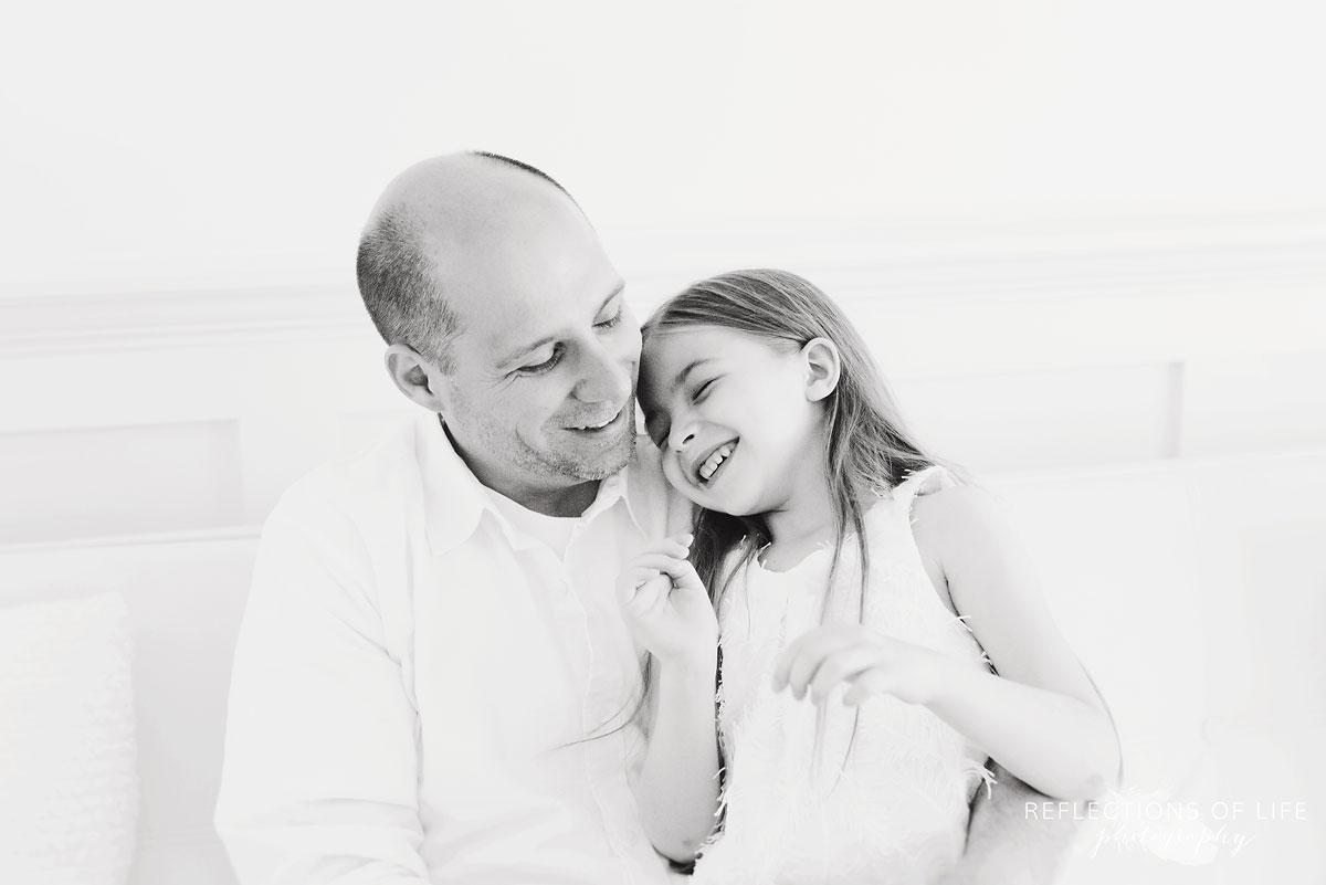 father and daughter talking while sitting on white couch