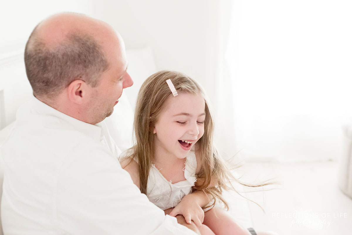 daughter and father laughing together in white studio